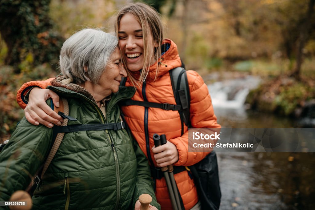 Senior women and her granddaughter hiking on mountain, walking through forest