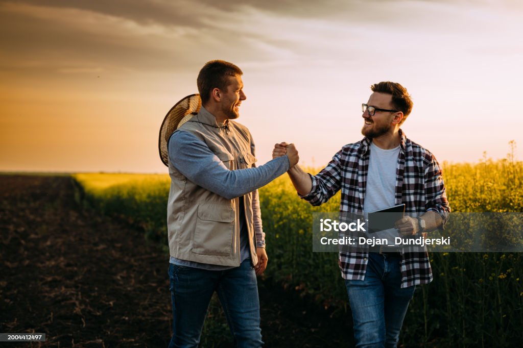 A Farmer and his business partner greet each other on the field
