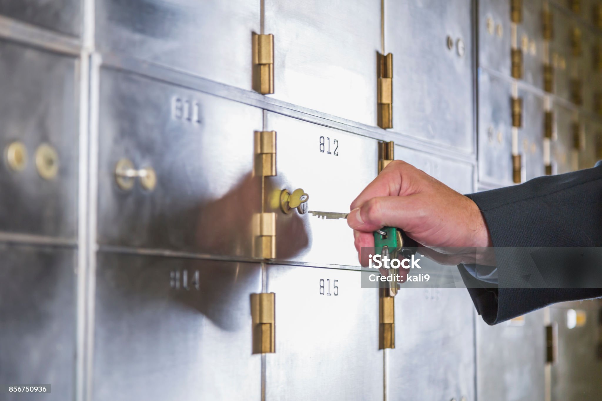 Hand of a mature man opening a safety deposit box. He is turning the key in the lock.