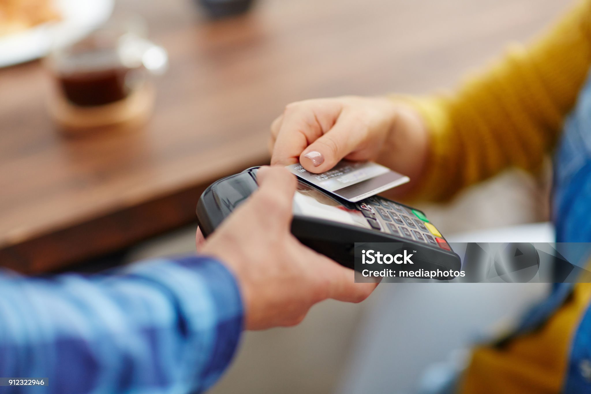 Close-up of unrecognizable customer choosing contactless payment using credit card while waitress accepting payment over nfc technology