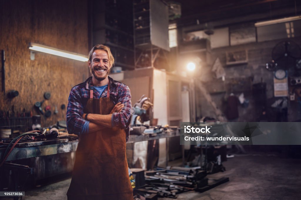Portrait of smiling mechanic standing in garage workshop with professional equipment